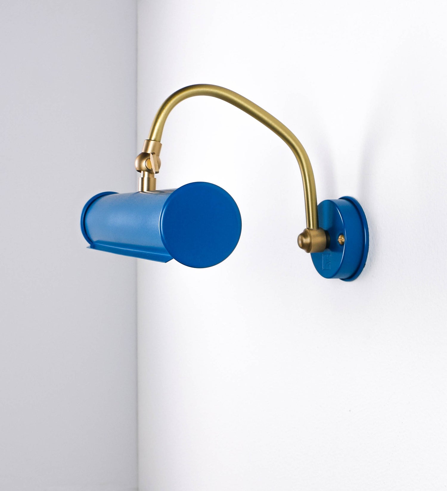 Aplique de parede que combina elementos clássicos com toques contemporâneos. O aplique é composto por uma base circular azul vintage de onde se estende um braço curvo e gracioso, em latão escovado, que suporta a barra principal. O braço contém um elemento, em latão escovado, que permite apertar ou desapertar a barra para melhor manipular a direção da luz. A barra de 25cm de largura, é cilíndrica e alongada, azul vintage. As extremidades do cilindro são planas e do mesmo diâmetro.