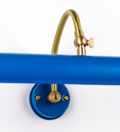 Aplique de parede que combina elementos clássicos com toques contemporâneos. O aplique é composto por uma base circular azul vintage de onde se estende um braço curvo e gracioso, em latão escovado, que suporta a barra principal. O braço contém um elemento, em latão escovado, que permite apertar ou desapertar a barra para melhor manipular a direção da luz. A barra de 25cm de largura, é cilíndrica e alongada, azul vintage. As extremidades do cilindro são planas e do mesmo diâmetro.