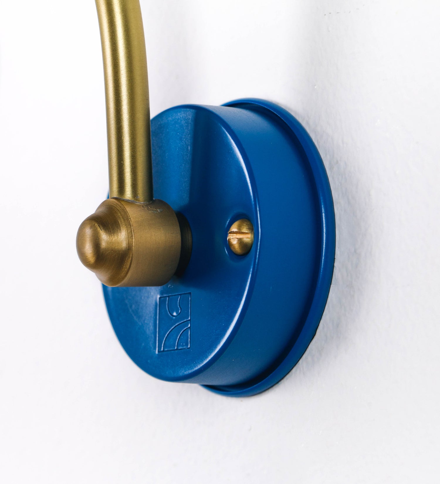 Aplique de parede que combina elementos clássicos com toques contemporâneos. O aplique é composto por uma base circular azul vintage de onde se estende um braço curvo e gracioso, em latão escovado, que suporta a barra principal. O braço contém um elemento, em latão escovado, que permite apertar ou desapertar a barra para melhor manipular a direção da luz. A barra de 25cm de largura, é cilíndrica e alongada, azul vintage. As extremidades do cilindro são planas e do mesmo diâmetro.