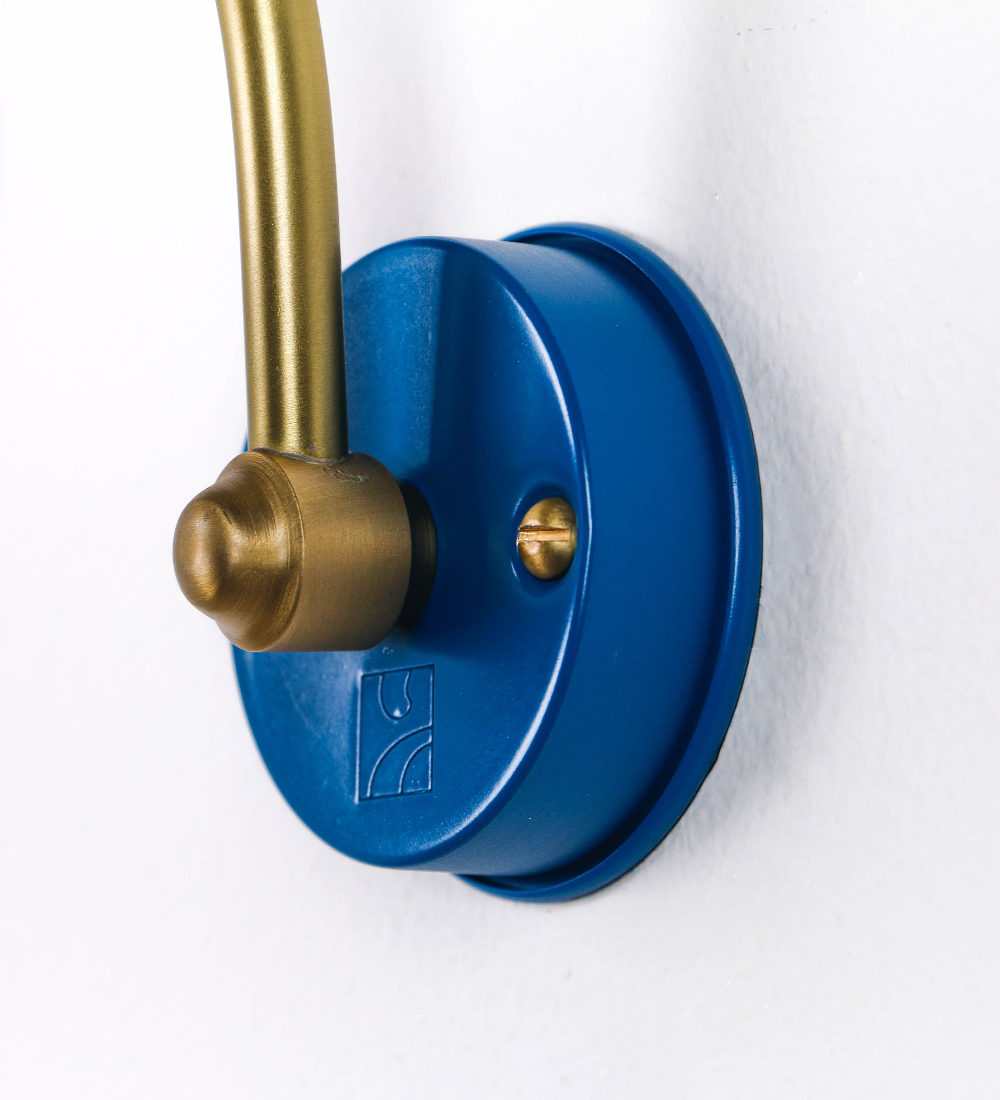 Aplique de parede que combina elementos clássicos com toques contemporâneos. O aplique é composto por uma base circular azul vintage de onde se estende um braço curvo e gracioso, em latão escovado, que suporta a barra principal. O braço contém um elemento, em latão escovado, que permite apertar ou desapertar a barra para melhor manipular a direção da luz. A barra de 25cm de largura, é cilíndrica e alongada, azul vintage. As extremidades do cilindro são planas e do mesmo diâmetro.
