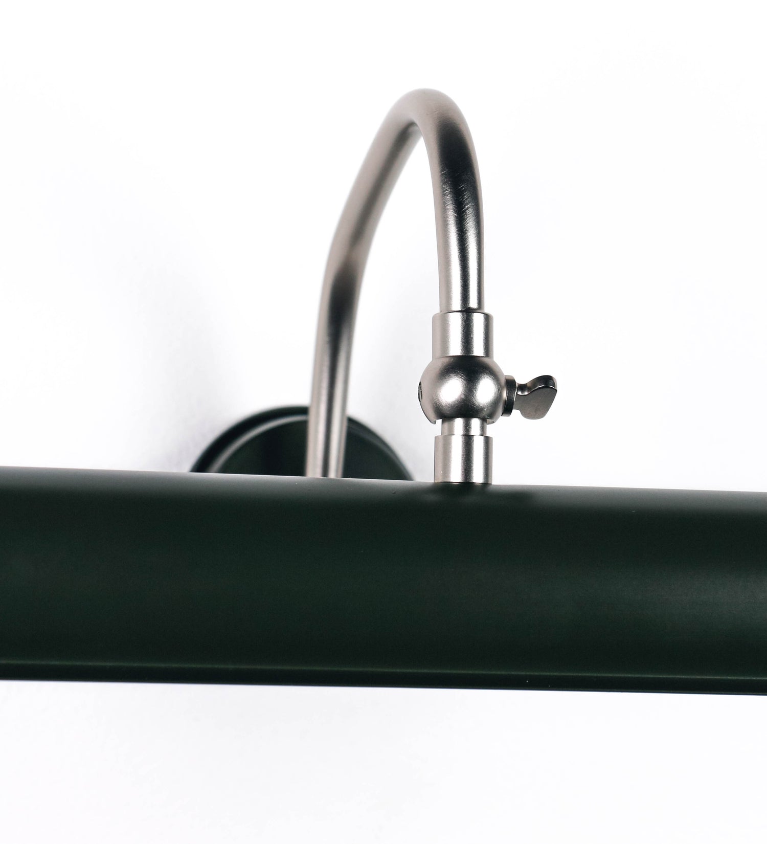 Aplique de parede que combina elementos clássicos com toques contemporâneos. O aplique é composto por uma base circular verde-azeitona, de onde se estende um braço curvo e gracioso, em níquel escovado, que suporta a barra principal. O braço contém um elemento, em níquel escovado, que permite apertar ou desapertar a barra para melhor manipular a direção da luz. A barra de 25cm de largura, é cilíndrica e alongada, verde-azeitona. As extremidades do cilindro são planas e do mesmo diâmetro.