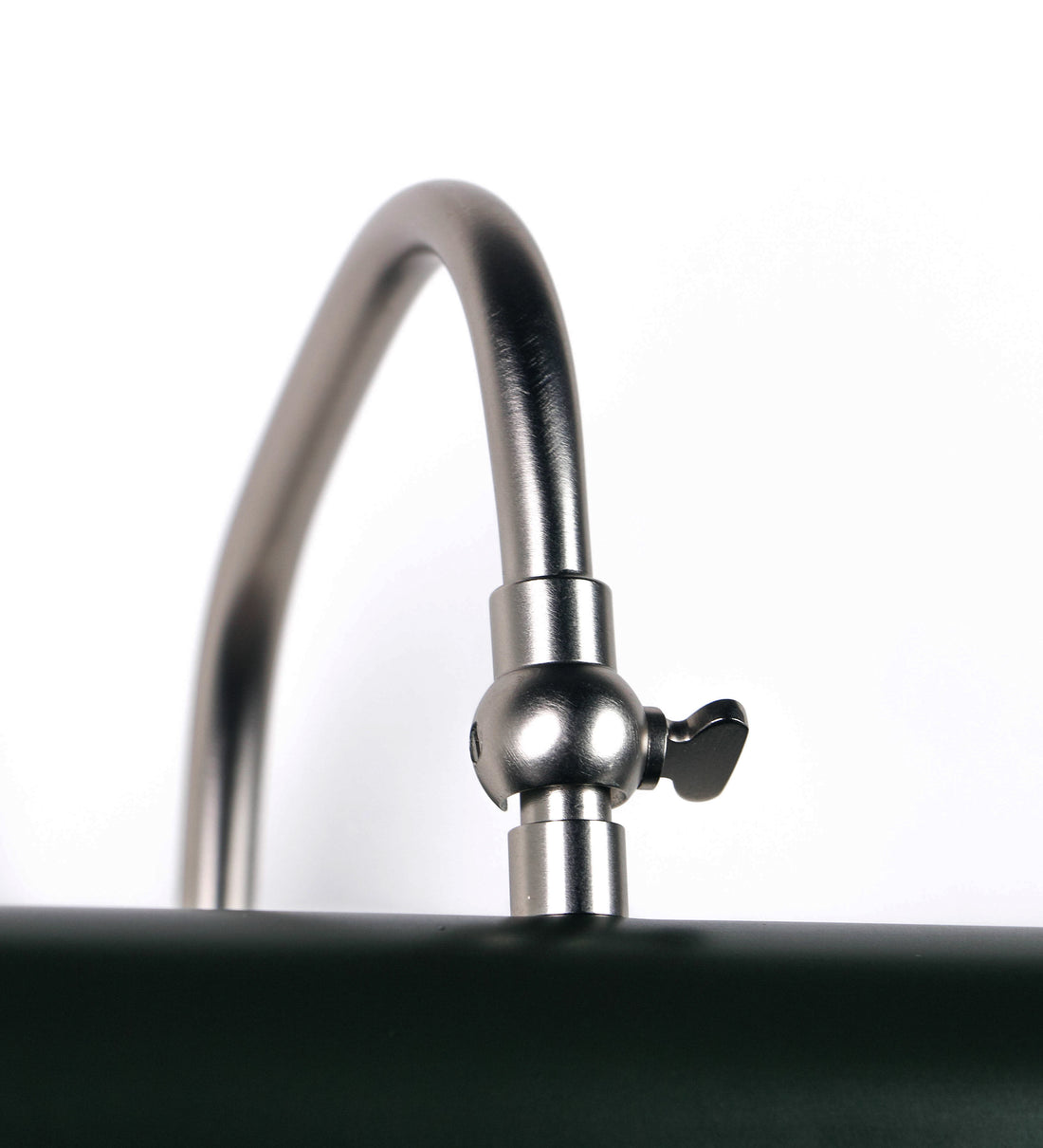 Aplique de parede que combina elementos clássicos com toques contemporâneos. O aplique é composto por uma base circular verde-azeitona, de onde se estende um braço curvo e gracioso, em níquel escovado, que suporta a barra principal. O braço contém um elemento, em níquel escovado, que permite apertar ou desapertar a barra para melhor manipular a direção da luz. A barra de 25cm de largura, é cilíndrica e alongada, verde-azeitona. As extremidades do cilindro são planas e do mesmo diâmetro.
