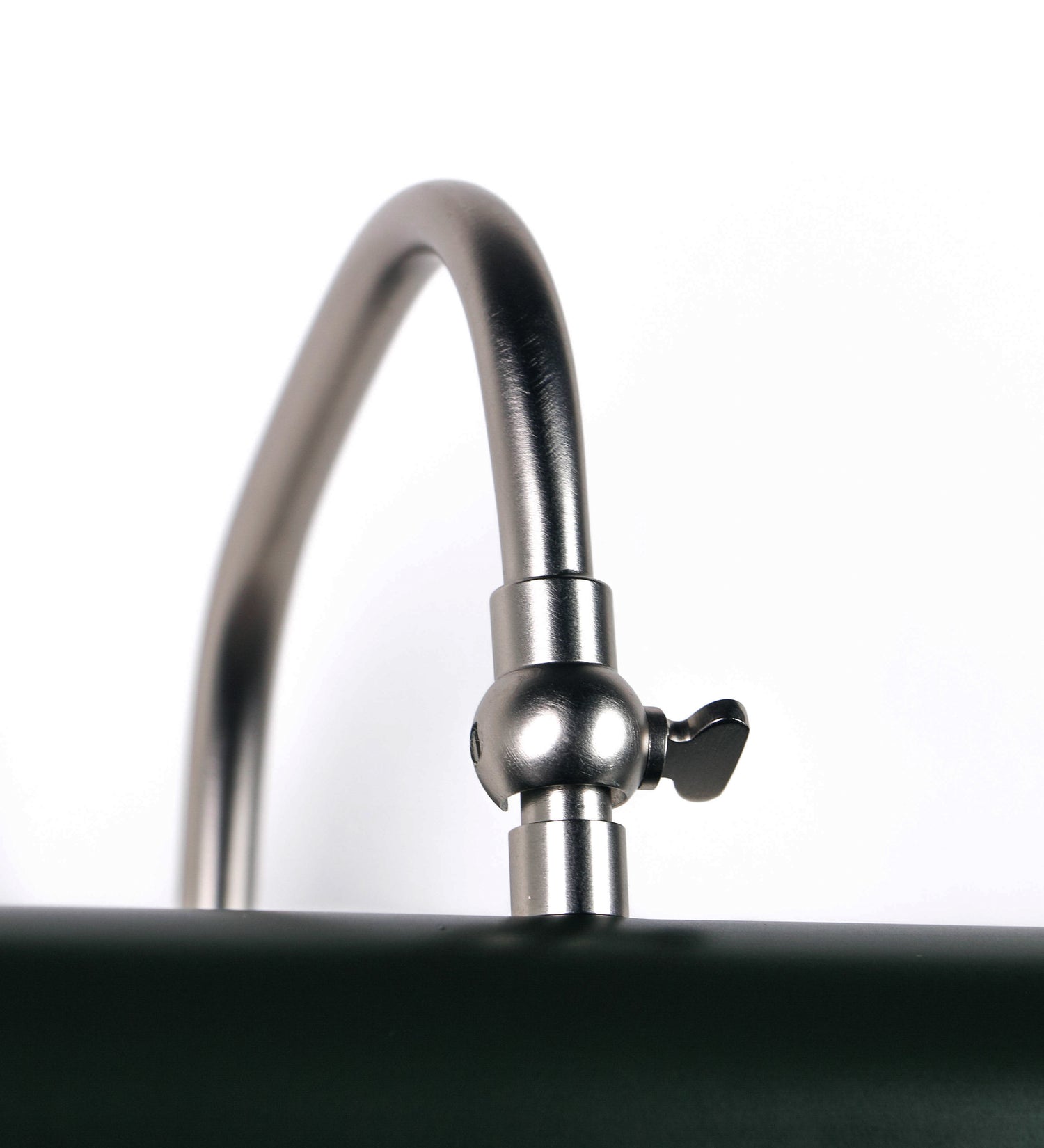 Aplique de parede que combina elementos clássicos com toques contemporâneos. O aplique é composto por uma base circular verde-azeitona, de onde se estende um braço curvo e gracioso, em níquel escovado, que suporta a barra principal. O braço contém um elemento, em níquel escovado, que permite apertar ou desapertar a barra para melhor manipular a direção da luz. A barra de 25cm de largura, é cilíndrica e alongada, verde-azeitona. As extremidades do cilindro são planas e do mesmo diâmetro.