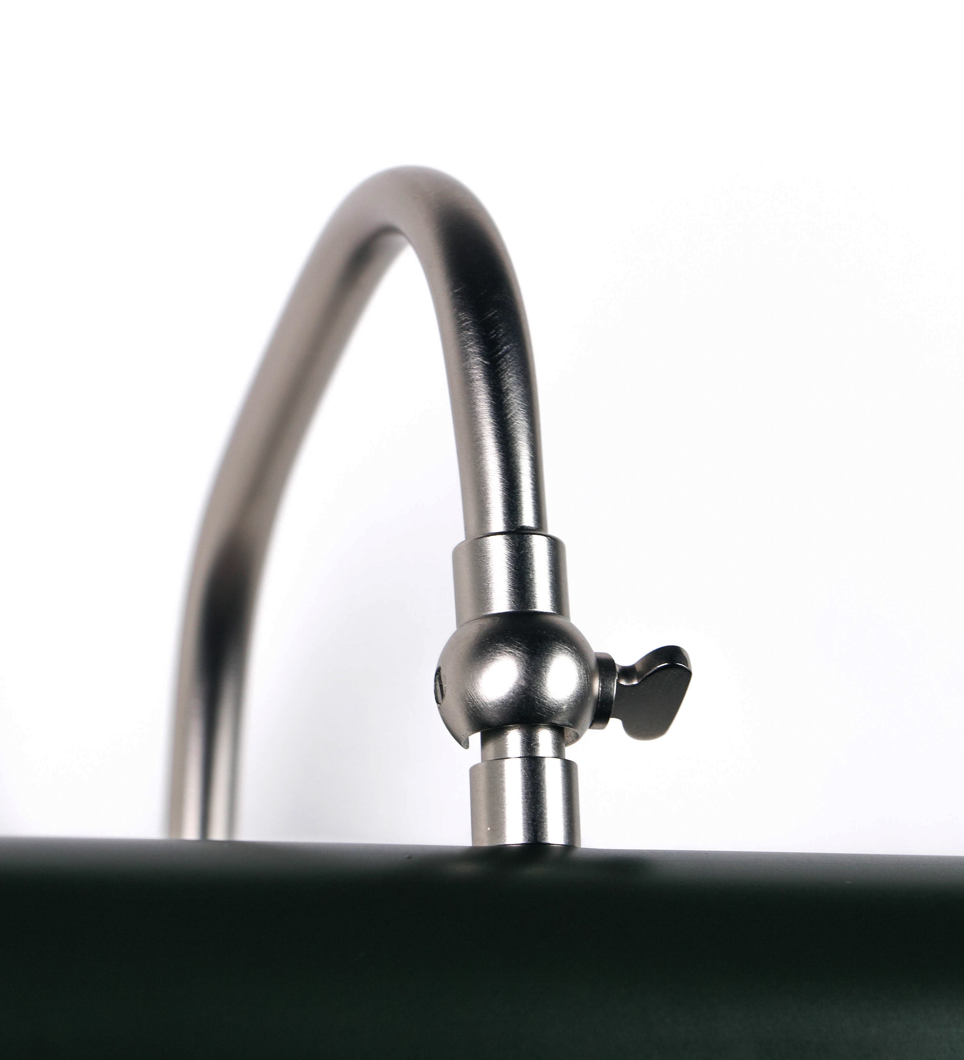 Aplique de parede que combina elementos clássicos com toques contemporâneos. O aplique é composto por uma base circular verde-azeitona, de onde se estende um braço curvo e gracioso, em níquel escovado, que suporta a barra principal. O braço contém um elemento, em níquel escovado, que permite apertar ou desapertar a barra para melhor manipular a direção da luz. A barra de 25cm de largura, é cilíndrica e alongada, verde-azeitona. As extremidades do cilindro são planas e do mesmo diâmetro.