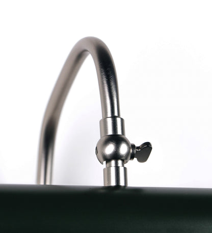 Aplique de parede que combina elementos clássicos com toques contemporâneos. O aplique é composto por uma base circular verde-azeitona, de onde se estende um braço curvo e gracioso, em níquel escovado, que suporta a barra principal. O braço contém um elemento, em níquel escovado, que permite apertar ou desapertar a barra para melhor manipular a direção da luz. A barra de 25cm de largura, é cilíndrica e alongada, verde-azeitona. As extremidades do cilindro são planas e do mesmo diâmetro.