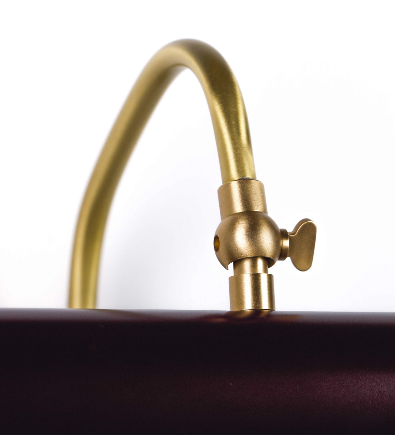 Aplique de parede que combina elementos clássicos com toques contemporâneos. O aplique é composto por uma base circular tom vinho, de onde se estende um braço curvo e gracioso, em latão escovado, que suporta a barra principal. O braço contém um elemento, em latão escovado, que permite apertar ou desapertar a barra para melhor manipular a direção da luz. A barra de 25cm de largura, é cilíndrica e alongada, tom vinho. As extremidades do cilindro são planas e do mesmo diâmetro.