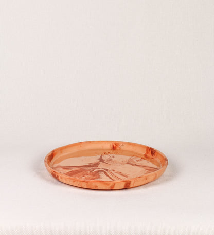 Prato raso com design minimalista e distinto. O prato é de barro, com uma mistura dois tipos de barro diferentes, um mais escuro e outro mais claro. Esta mistura cria um desenho de formas abstratas e aleatórias, que se espalham por todas as superfícies do prato. Tem um acabamento vidrado transparente com brilho, conferindo um toque de sofisticação e preservando os tons naturais dos barros. A forma do prato é circular, com uma borda envolvente de altura baixa e design simples e minimalista. 