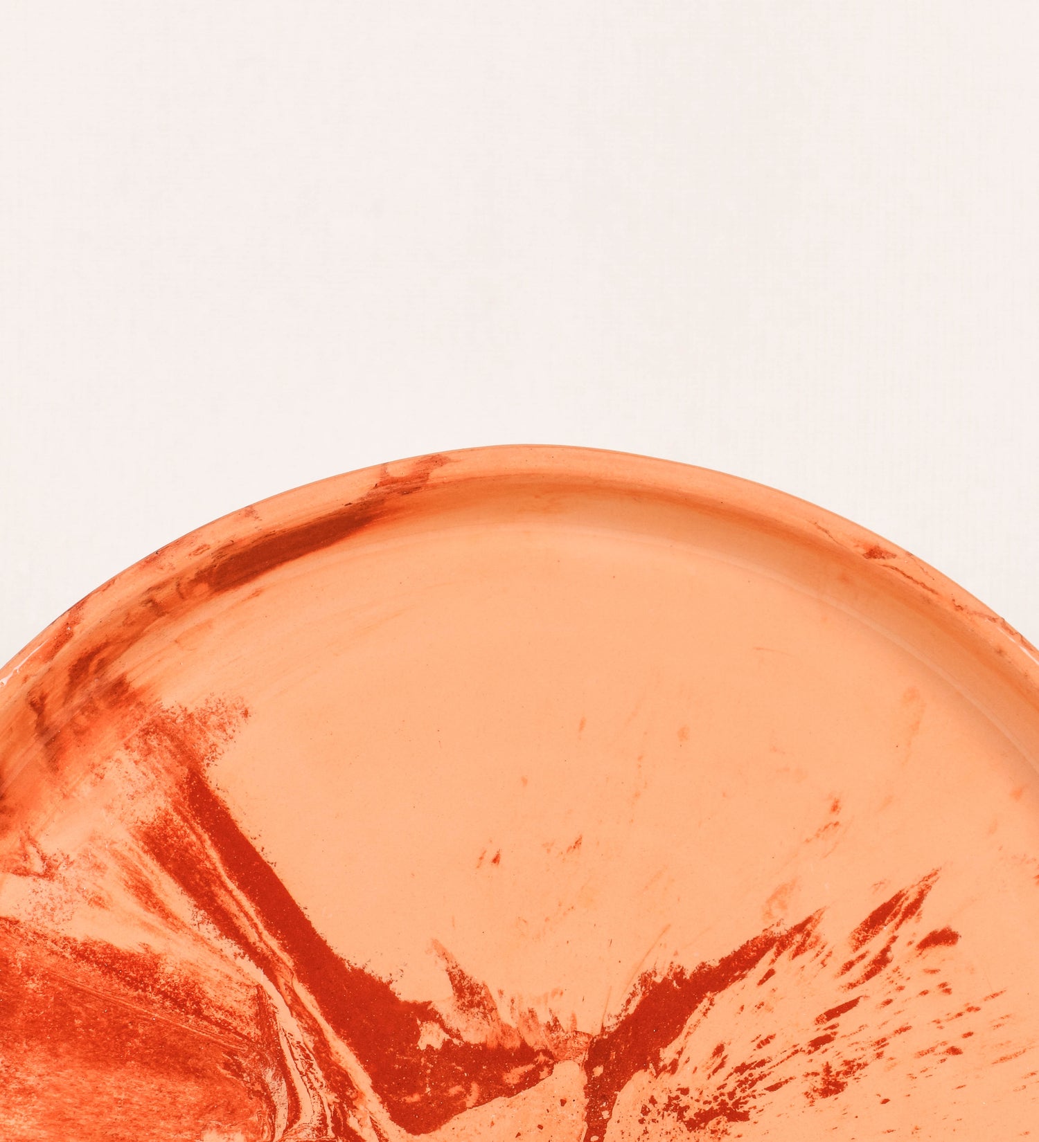 Prato raso com design minimalista e distinto. O prato é de barro, com uma mistura dois tipos de barro diferentes, um mais escuro e outro mais claro. Esta mistura cria um desenho de formas abstratas e aleatórias, que se espalham por todas as superfícies do prato. Tem um acabamento vidrado transparente com brilho, conferindo um toque de sofisticação e preservando os tons naturais dos barros. A forma do prato é circular, com uma borda envolvente de altura baixa e design simples e minimalista. 