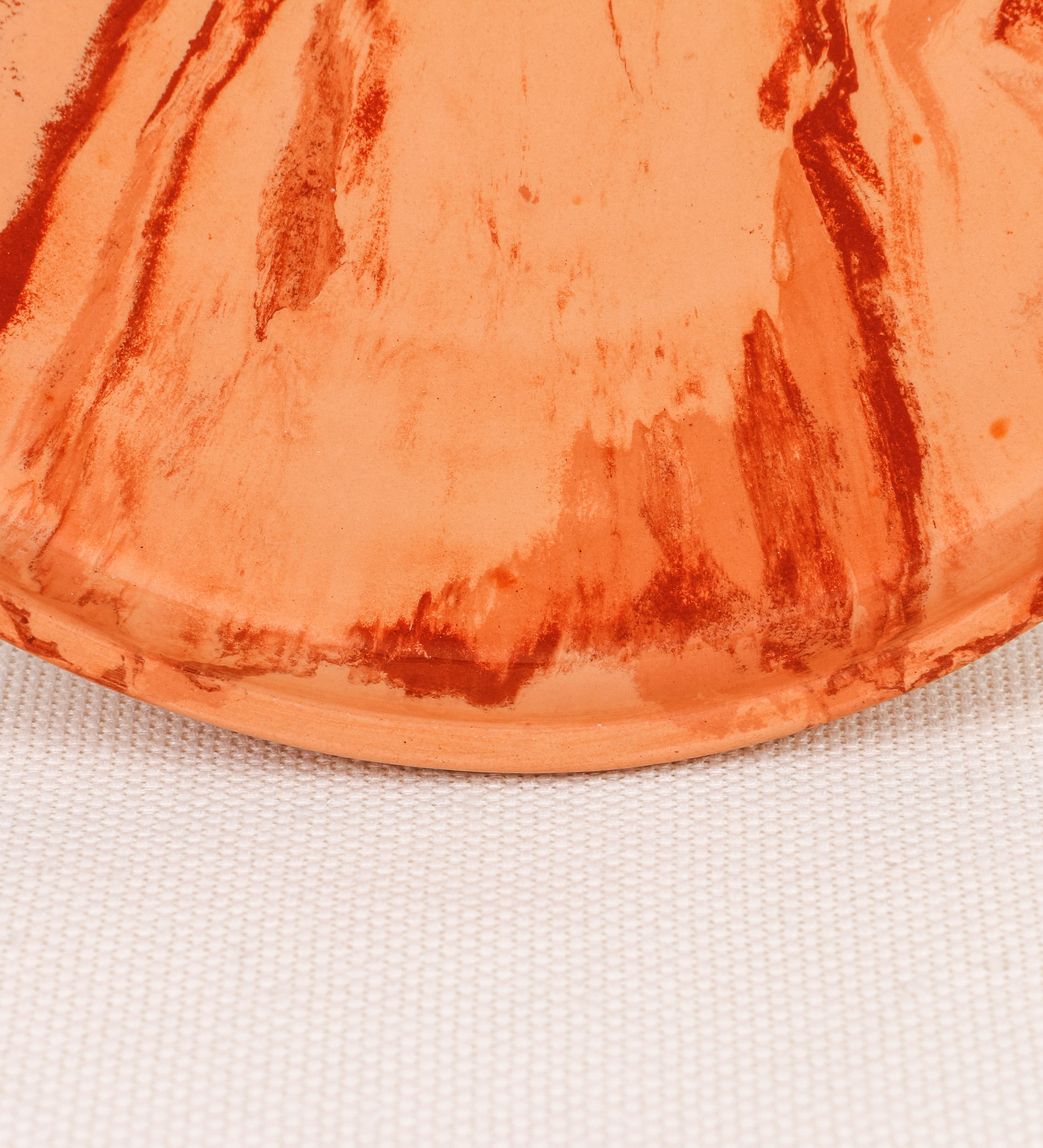 Prato raso com design minimalista e distinto. O prato é de barro, com uma mistura dois tipos de barro diferentes, um mais escuro e outro mais claro. Esta mistura cria um desenho de formas abstratas e aleatórias, que se espalham por todas as superfícies do prato. Tem um acabamento vidrado transparente com brilho, conferindo um toque de sofisticação e preservando os tons naturais dos barros. A forma do prato é circular, com uma borda envolvente de altura baixa e design simples e minimalista. 