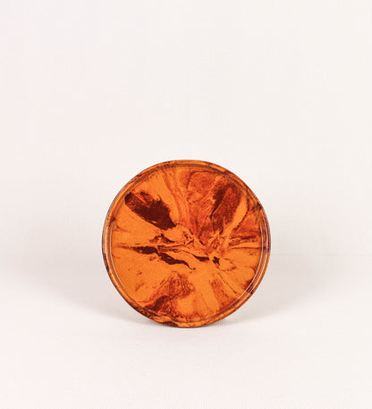 Prato de aperitivos com design minimalista e distinto. O prato é de barro, com uma mistura de dois tipos de barro diferentes, um mais escuro e outro mais claro. Esta mistura cria um desenho de formas abstratas e aleatórias, que se espalham por todas as superfícies do prato. Tem acabamento vidrado castanho translúcido, escurecendo as cores originais dos barros misturados. A forma do prato é circular, com uma borda envolvente de altura baixa e design simples e minimalista. 