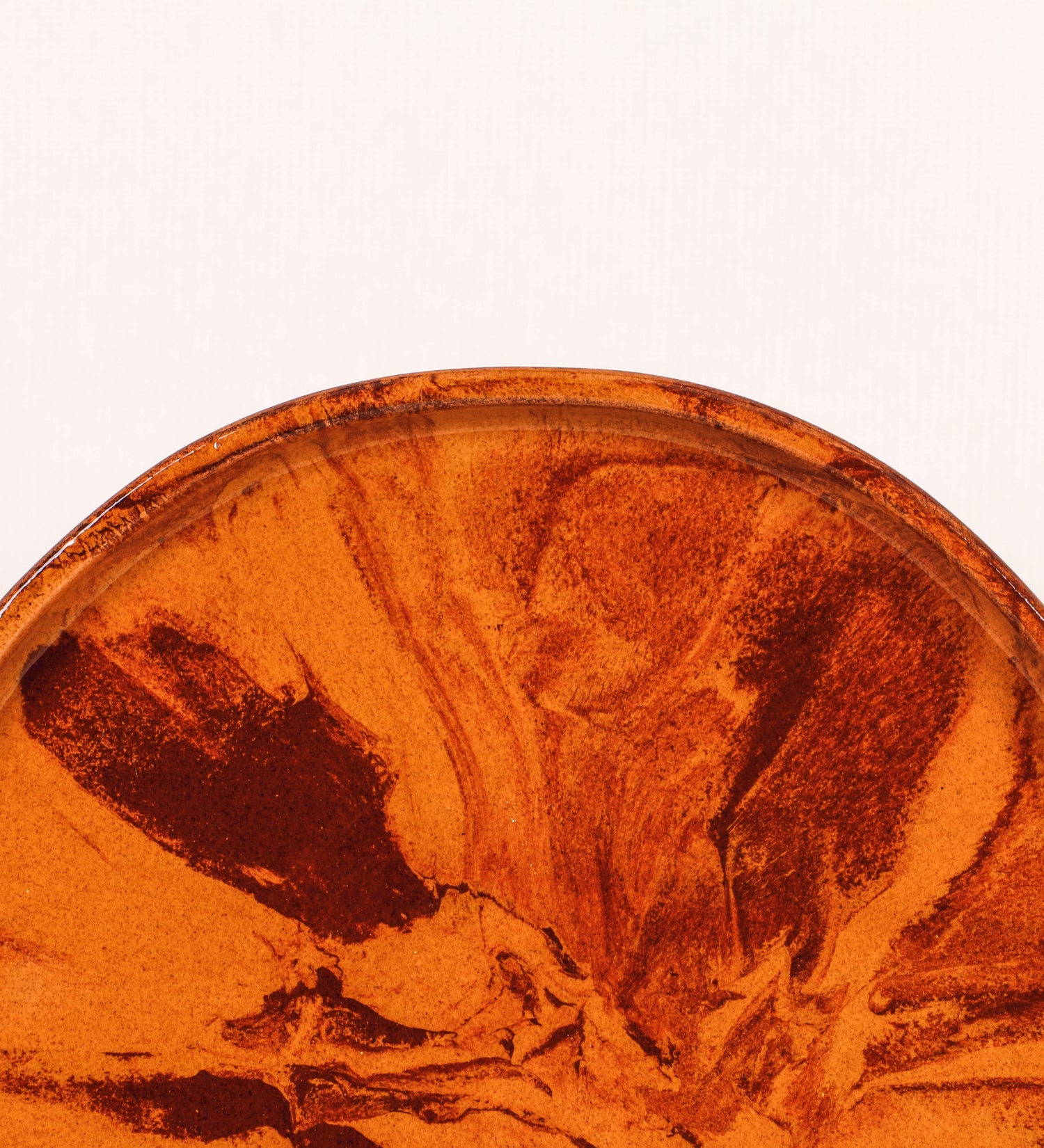 Prato de aperitivos com design minimalista e distinto. O prato é de barro, com uma mistura de dois tipos de barro diferentes, um mais escuro e outro mais claro. Esta mistura cria um desenho de formas abstratas e aleatórias, que se espalham por todas as superfícies do prato. Tem acabamento vidrado castanho translúcido, escurecendo as cores originais dos barros misturados. A forma do prato é circular, com uma borda envolvente de altura baixa e design simples e minimalista. 