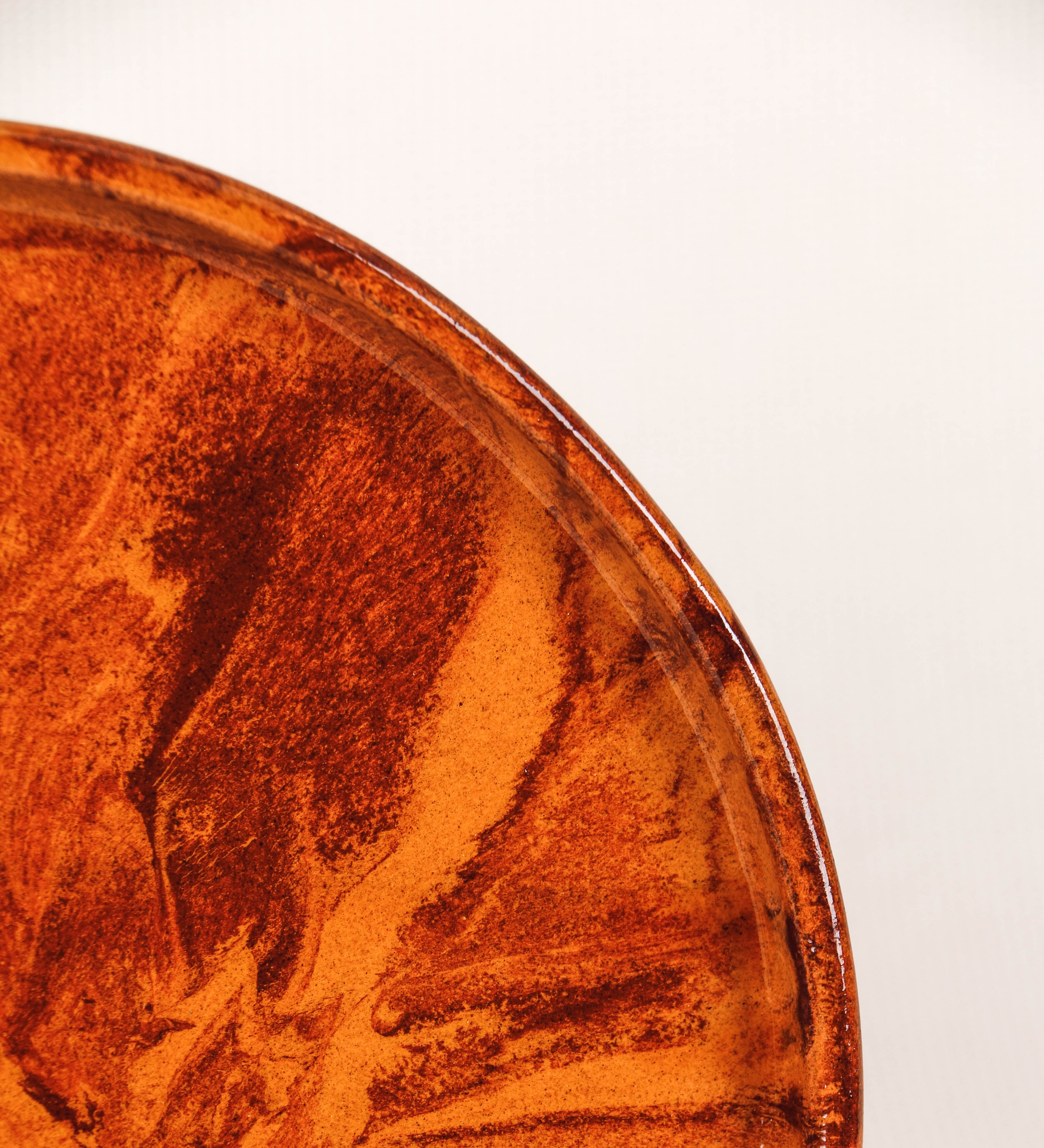 Prato de aperitivos com design minimalista e distinto. O prato é de barro, com uma mistura de dois tipos de barro diferentes, um mais escuro e outro mais claro. Esta mistura cria um desenho de formas abstratas e aleatórias, que se espalham por todas as superfícies do prato. Tem acabamento vidrado castanho translúcido, escurecendo as cores originais dos barros misturados. A forma do prato é circular, com uma borda envolvente de altura baixa e design simples e minimalista. 