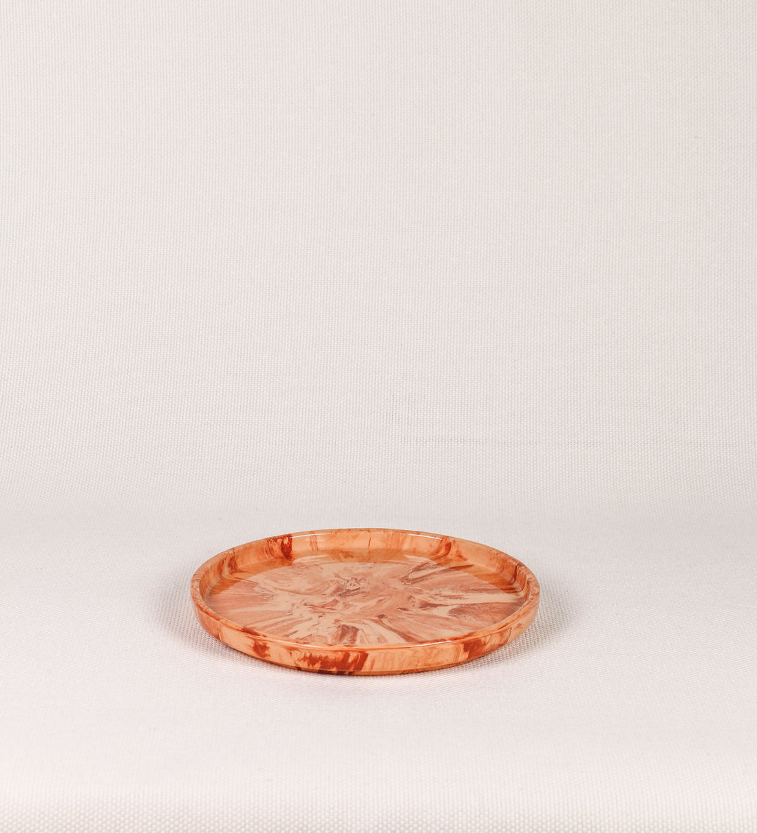 Prato de aperitivos com design minimalista e distinto. O prato é de barro, com uma mistura dois tipos de barro diferentes, um mais escuro e outro mais claro. Esta mistura cria um desenho de formas abstratas e aleatórias, que se espalham por todas as superfícies do prato. Tem um acabamento vidrado transparente com brilho, conferindo um toque de sofisticação e preservando os tons naturais dos barros. A forma do prato é circular, com uma borda envolvente de altura baixa e design simples e minimalista. 