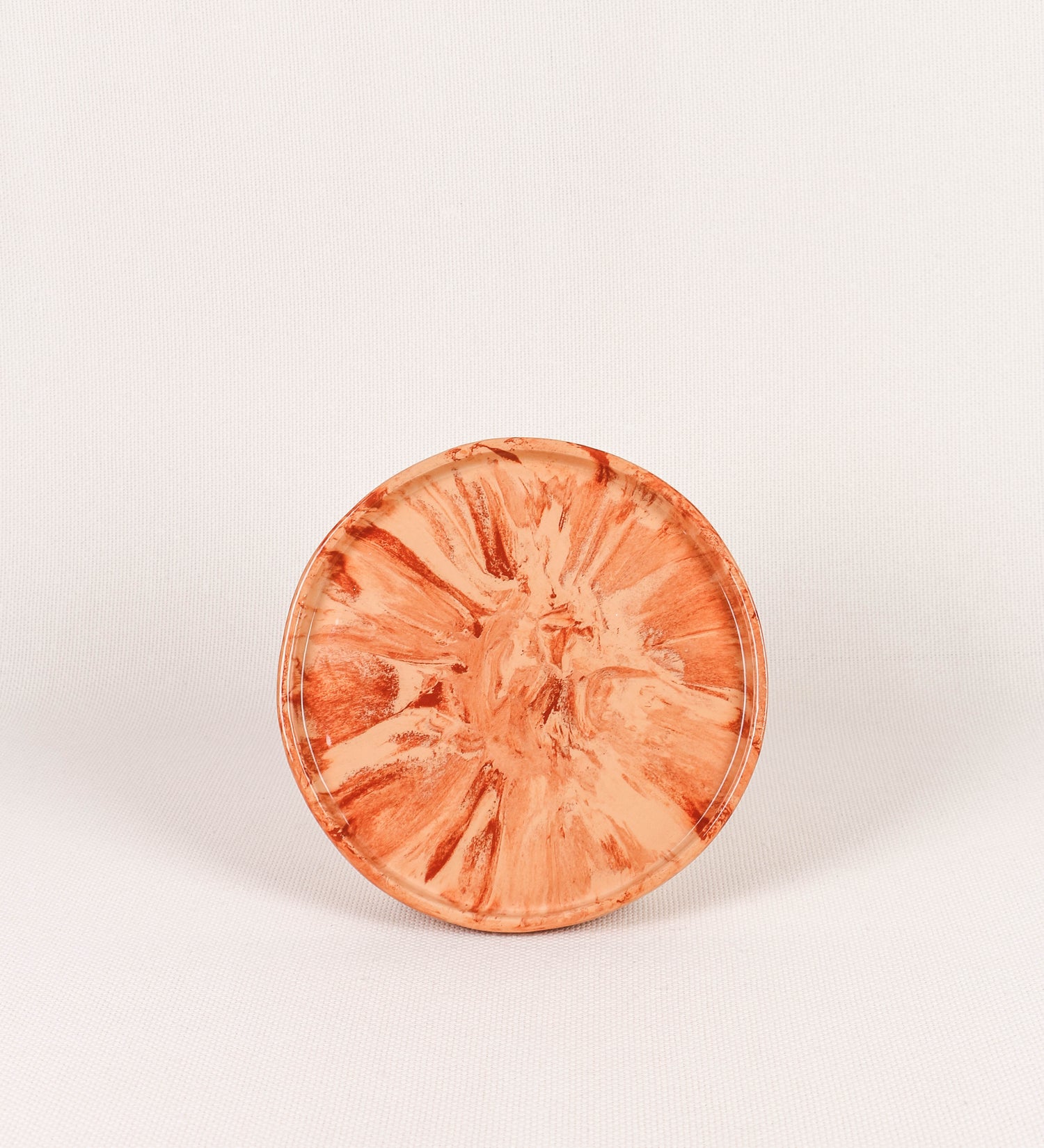Prato de aperitivos com design minimalista e distinto. O prato é de barro, com uma mistura dois tipos de barro diferentes, um mais escuro e outro mais claro. Esta mistura cria um desenho de formas abstratas e aleatórias, que se espalham por todas as superfícies do prato. Tem um acabamento vidrado transparente com brilho, conferindo um toque de sofisticação e preservando os tons naturais dos barros. A forma do prato é circular, com uma borda envolvente de altura baixa e design simples e minimalista. 