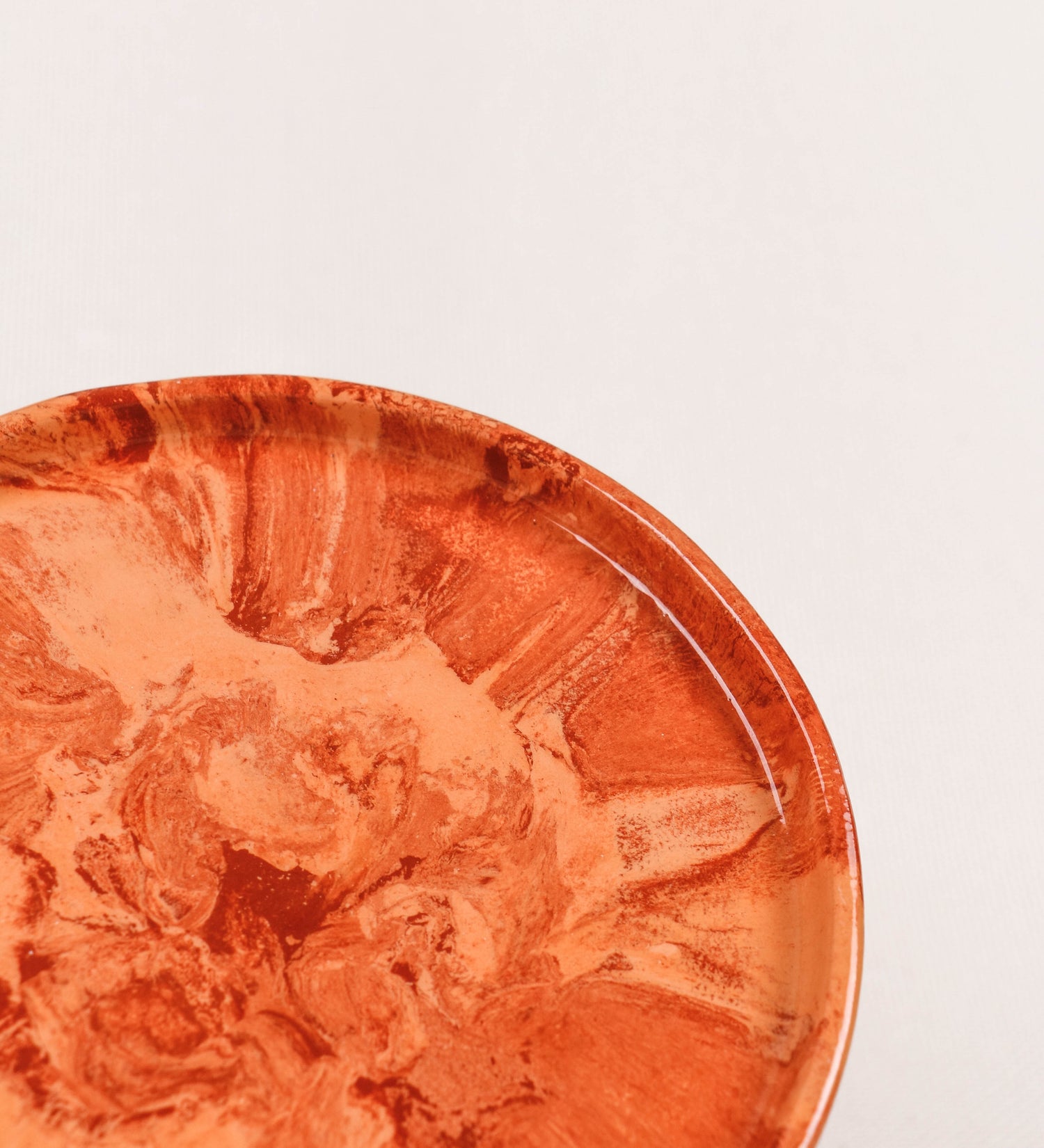 Prato de aperitivos com design minimalista e distinto. O prato é de barro, com uma mistura dois tipos de barro diferentes, um mais escuro e outro mais claro. Esta mistura cria um desenho de formas abstratas e aleatórias, que se espalham por todas as superfícies do prato. Tem um acabamento vidrado transparente com brilho, conferindo um toque de sofisticação e preservando os tons naturais dos barros. A forma do prato é circular, com uma borda envolvente de altura baixa e design simples e minimalista. 