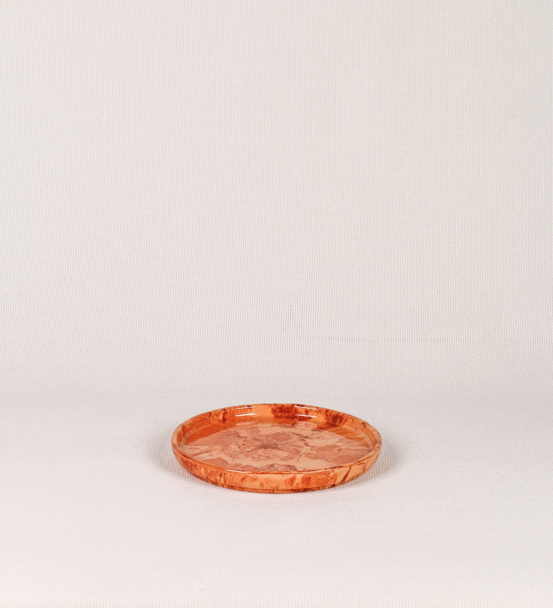 Prato de sobremesa com design minimalista e distinto. O prato é de barro, com uma mistura dois tipos de barro diferentes, um mais escuro e outro mais claro. Esta mistura cria um desenho de formas abstratas e aleatórias, que se espalham por todas as superfícies do prato. Tem um acabamento vidrado transparente com brilho, conferindo um toque de sofisticação e preservando os tons naturais dos barros. A forma do prato é circular, com uma borda envolvente de altura baixa e design simples e minimalista. 