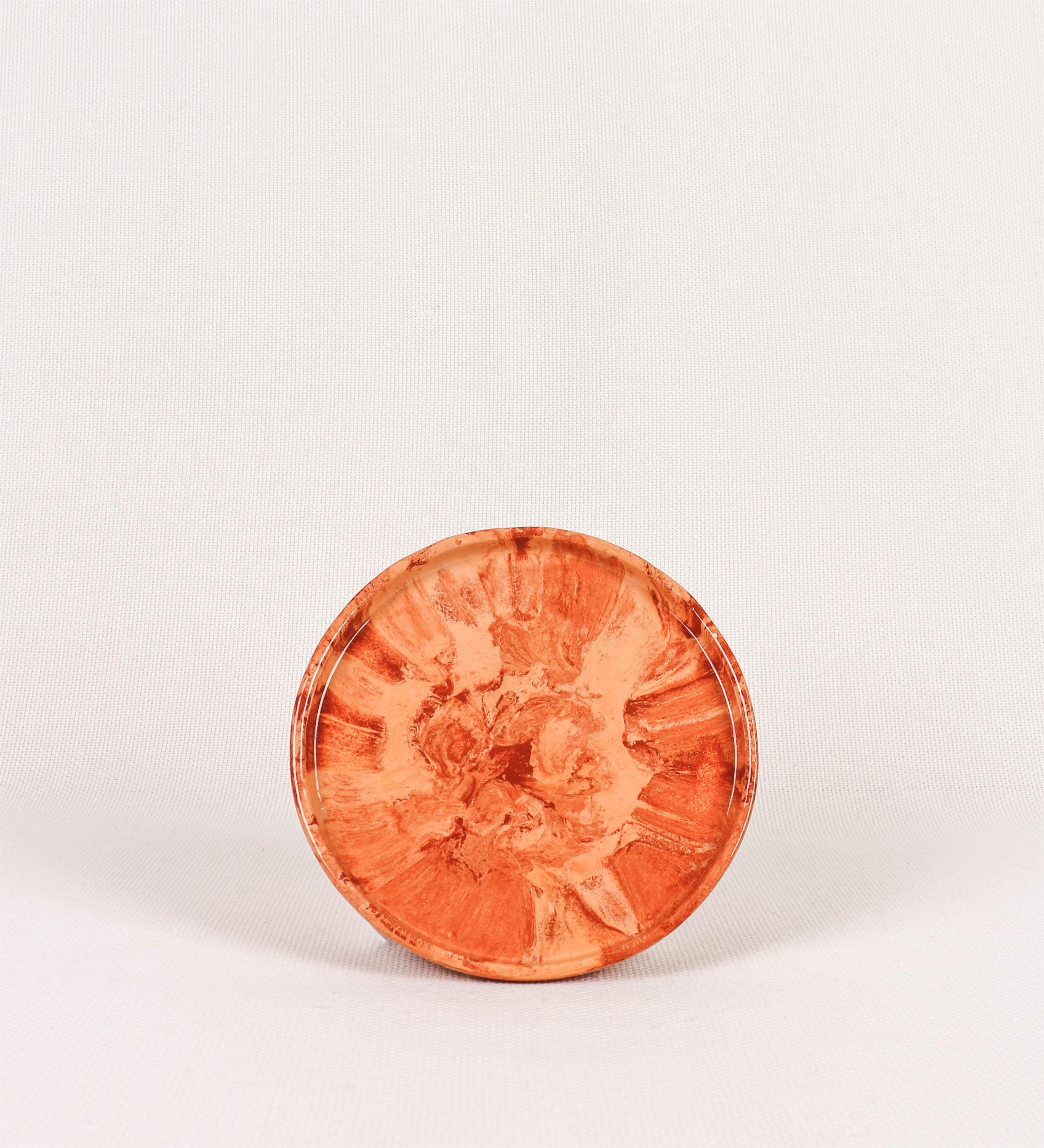 Prato de sobremesa com design minimalista e distinto. O prato é de barro, com uma mistura dois tipos de barro diferentes, um mais escuro e outro mais claro. Esta mistura cria um desenho de formas abstratas e aleatórias, que se espalham por todas as superfícies do prato. Tem um acabamento vidrado transparente com brilho, conferindo um toque de sofisticação e preservando os tons naturais dos barros. A forma do prato é circular, com uma borda envolvente de altura baixa e design simples e minimalista. 
