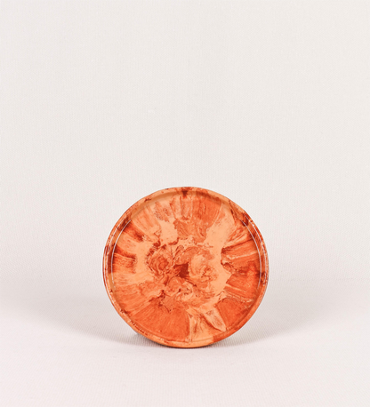 Prato de sobremesa com design minimalista e distinto. O prato é de barro, com uma mistura dois tipos de barro diferentes, um mais escuro e outro mais claro. Esta mistura cria um desenho de formas abstratas e aleatórias, que se espalham por todas as superfícies do prato. Tem um acabamento vidrado transparente com brilho, conferindo um toque de sofisticação e preservando os tons naturais dos barros. A forma do prato é circular, com uma borda envolvente de altura baixa e design simples e minimalista. 