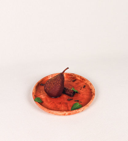Prato de sobremesa com design minimalista e distinto. O prato é de barro, com uma mistura dois tipos de barro diferentes, um mais escuro e outro mais claro. Esta mistura cria um desenho de formas abstratas e aleatórias, que se espalham por todas as superfícies do prato. Tem um acabamento vidrado transparente com brilho, conferindo um toque de sofisticação e preservando os tons naturais dos barros. A forma do prato é circular, com uma borda envolvente de altura baixa e design simples e minimalista. 