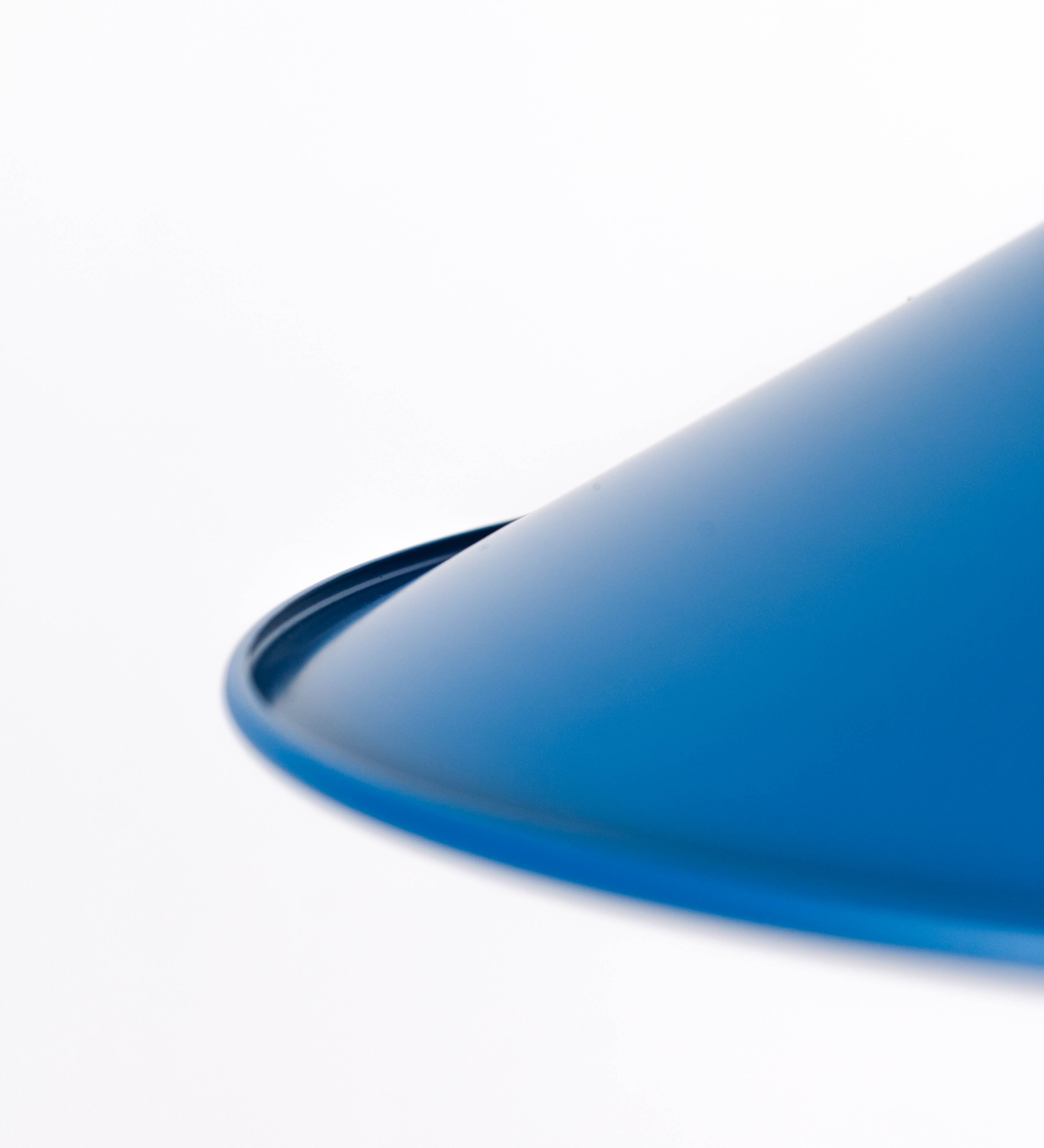 Suspensão de teto composta por uma base circular azul vintage de onde desce um cabo com padrão de linhas azuis e beges. O cabo passa por uma roldana em latão escovado fixa ao teto, e desce até ao chapéu. Entre a base e a roldana o cabo sustenta uma esfera em latão escovado, que atua como um contrapeso, para ajustar a altura. O chapéu, azul vintage, tem formato cónico invertido, uma borda ligeiramente levantada e interior branco. No topo do chapéu há um suporte em latão escovado que conecta o chapéu ao cabo.