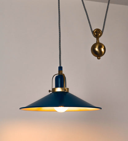 Suspensão de teto composta por uma base circular azul vintage de onde desce um cabo com padrão de linhas azuis e beges. O cabo passa por uma roldana em latão escovado fixa ao teto, e desce até ao chapéu. Entre a base e a roldana o cabo sustenta uma esfera em latão escovado, que atua como um contrapeso, para ajustar a altura. O chapéu, azul vintage, tem formato cónico invertido, uma borda ligeiramente levantada e interior branco. No topo do chapéu há um suporte em latão escovado que conecta o chapéu ao cabo.