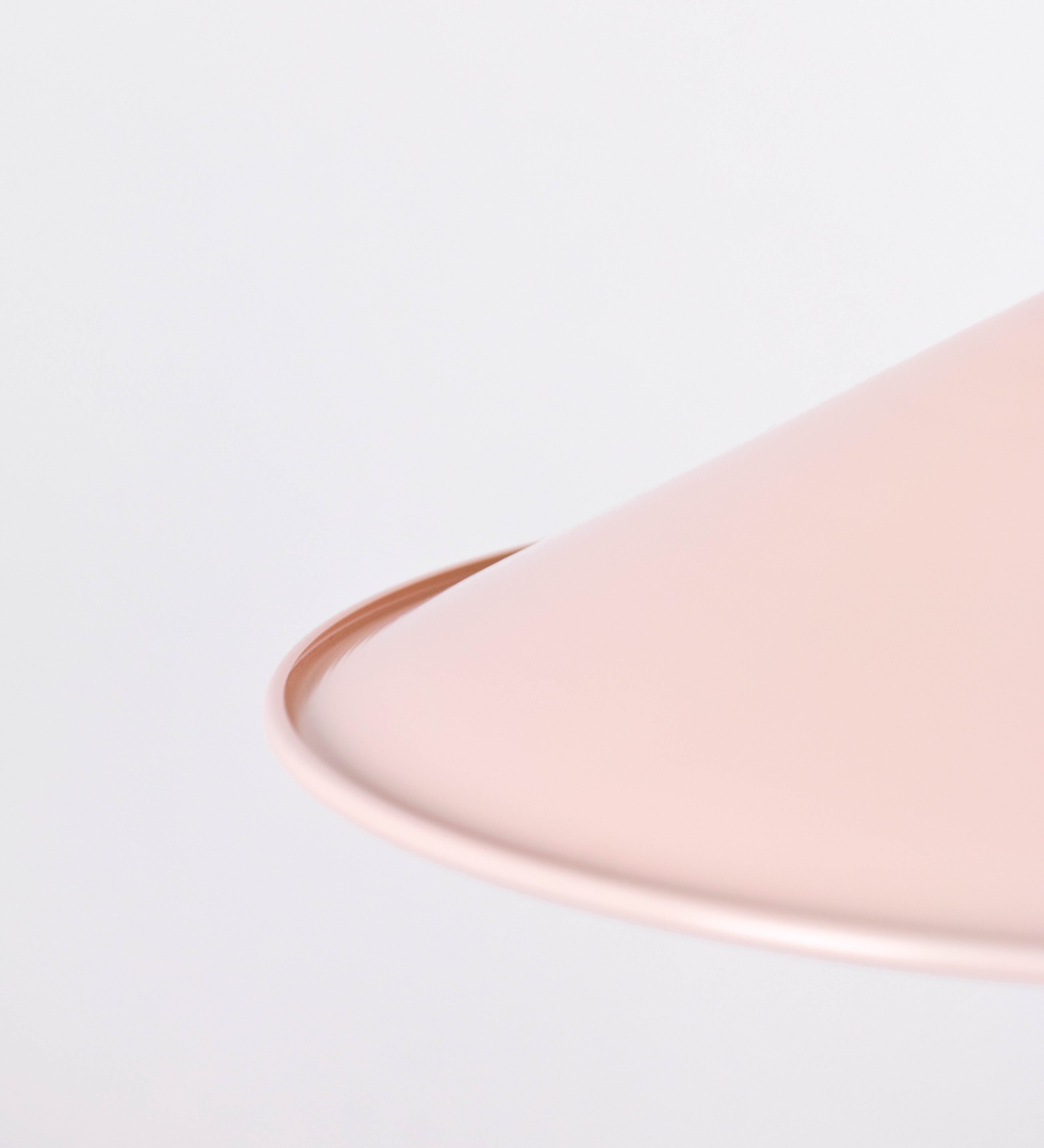 Suspensão de teto composta por uma base circular rosa clara, de onde desce um cabo revestido têxtil rosa velho. O cabo passa por uma roldana em níquel polido, fixa ao teto, e desce até ao chapéu. Entre a base e a roldana, o cabo sustenta uma esfera, em níquel polido, que atua como um contrapeso, para ajustar a altura. O chapéu, rosa claro, tem formato cónico invertido, uma borda ligeiramente levantada e interior branco. No topo do chapéu, há um suporte em níquel polido que conecta o chapéu ao cabo.