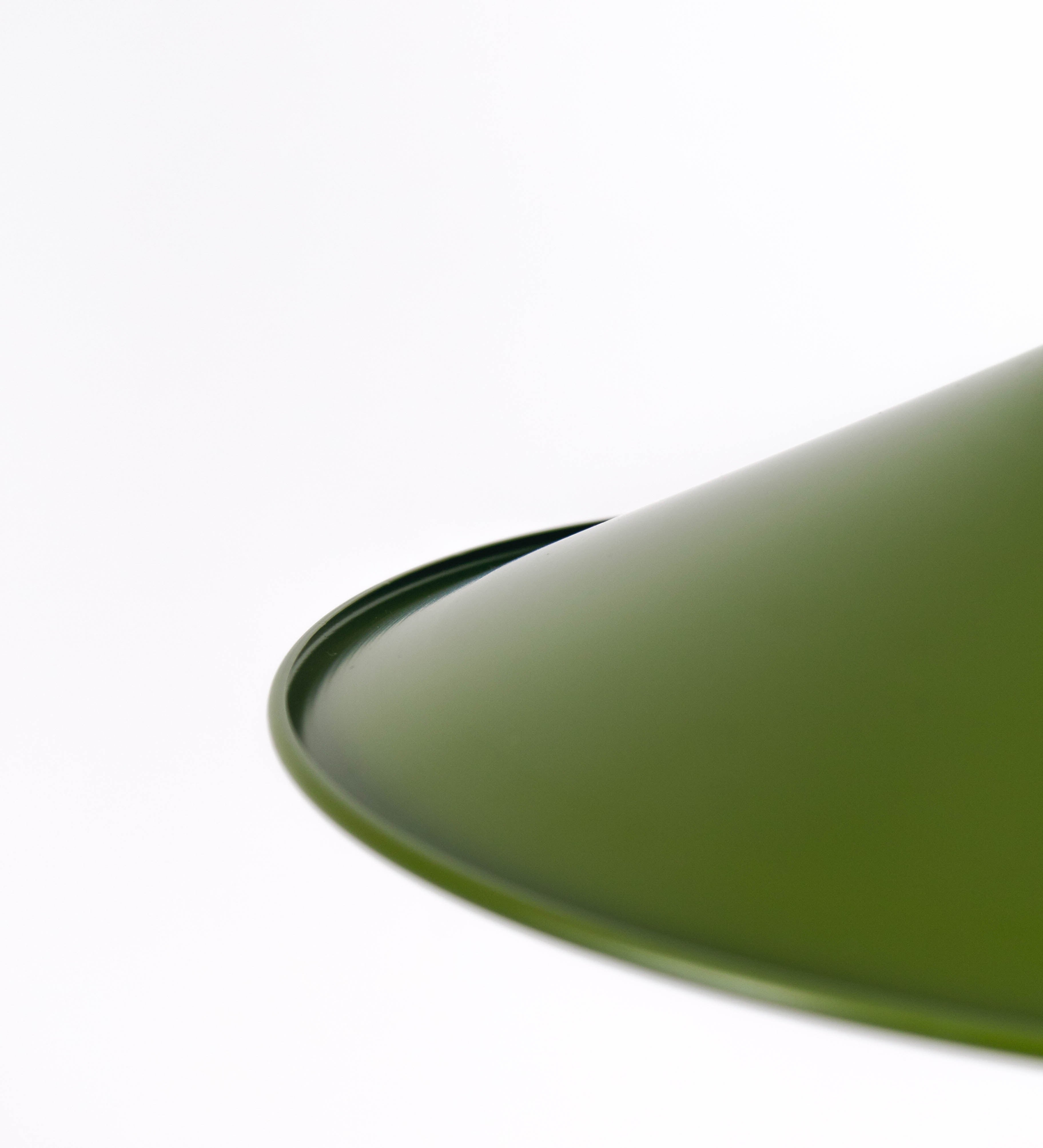 Suspensão de teto composta por uma base circular verde couve-de-bruxelas de onde desce um cabo com padrão de linhas castanhas e beges. O cabo passa por uma roldana em níquel escovado fixa ao teto, e desce até ao chapéu. Entre a base e a roldana o cabo sustenta uma esfera em níquel escovado, que atua como um contrapeso, para ajustar a altura. O chapéu é verde, de formato cónico invertido, uma borda levantada e interior branco. No topo do chapéu há um suporte em níquel escovado que conecta o chapéu ao cabo.