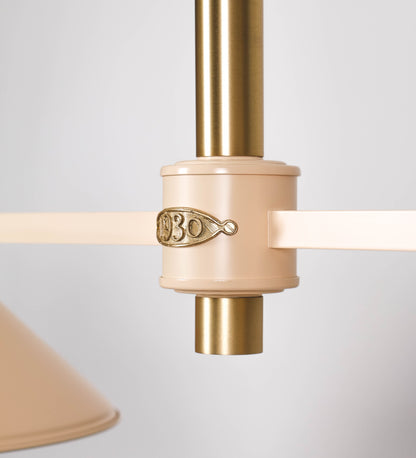 Suspensão de teto moderna e sofisticada. A suspensão é composta por uma base retangular em latão escovado, de onde desce um tubo cilíndrico até a estrutura principal e permite ajustar a altura da suspensão. A estrutura principal é composta por uma barra horizontal bege clara, que sustenta nas extremidades dois chapéus cónicos invertidos no mesmo tom, com interior em latão escovado. No centro da barra horizontal está uma pequena placa oval, em latão escovado, com o ano 1930 inscrito em relevo.