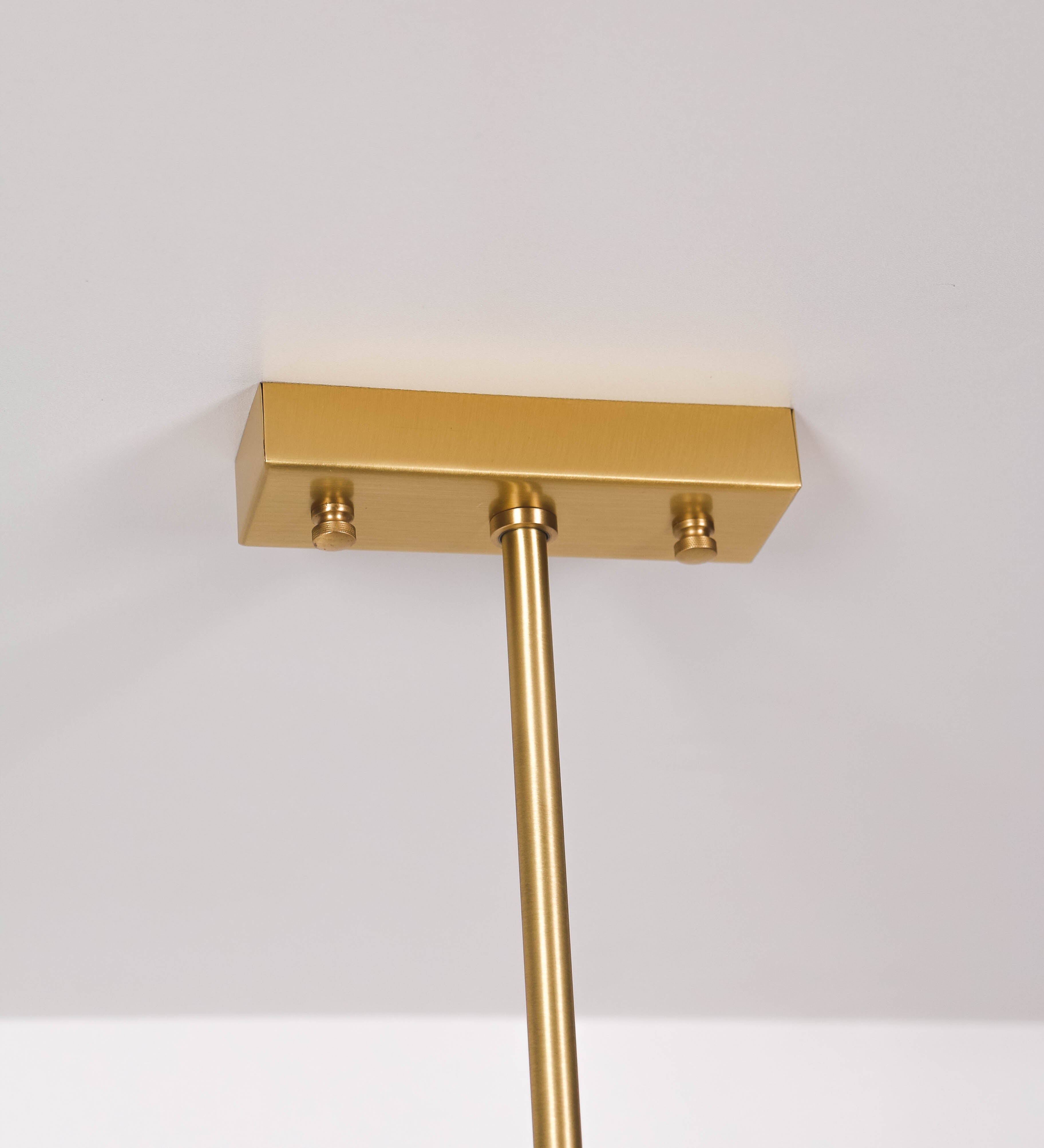 Suspensão de teto moderna e sofisticada. A suspensão é composta por uma base retangular em latão escovado, de onde desce um tubo cilíndrico até a estrutura principal e permite ajustar a altura da suspensão. A estrutura principal é composta por uma barra horizontal bege clara, que sustenta nas extremidades dois chapéus cónicos invertidos no mesmo tom, com interior em latão escovado. No centro da barra horizontal está uma pequena placa oval, em latão escovado, com o ano 1930 inscrito em relevo.