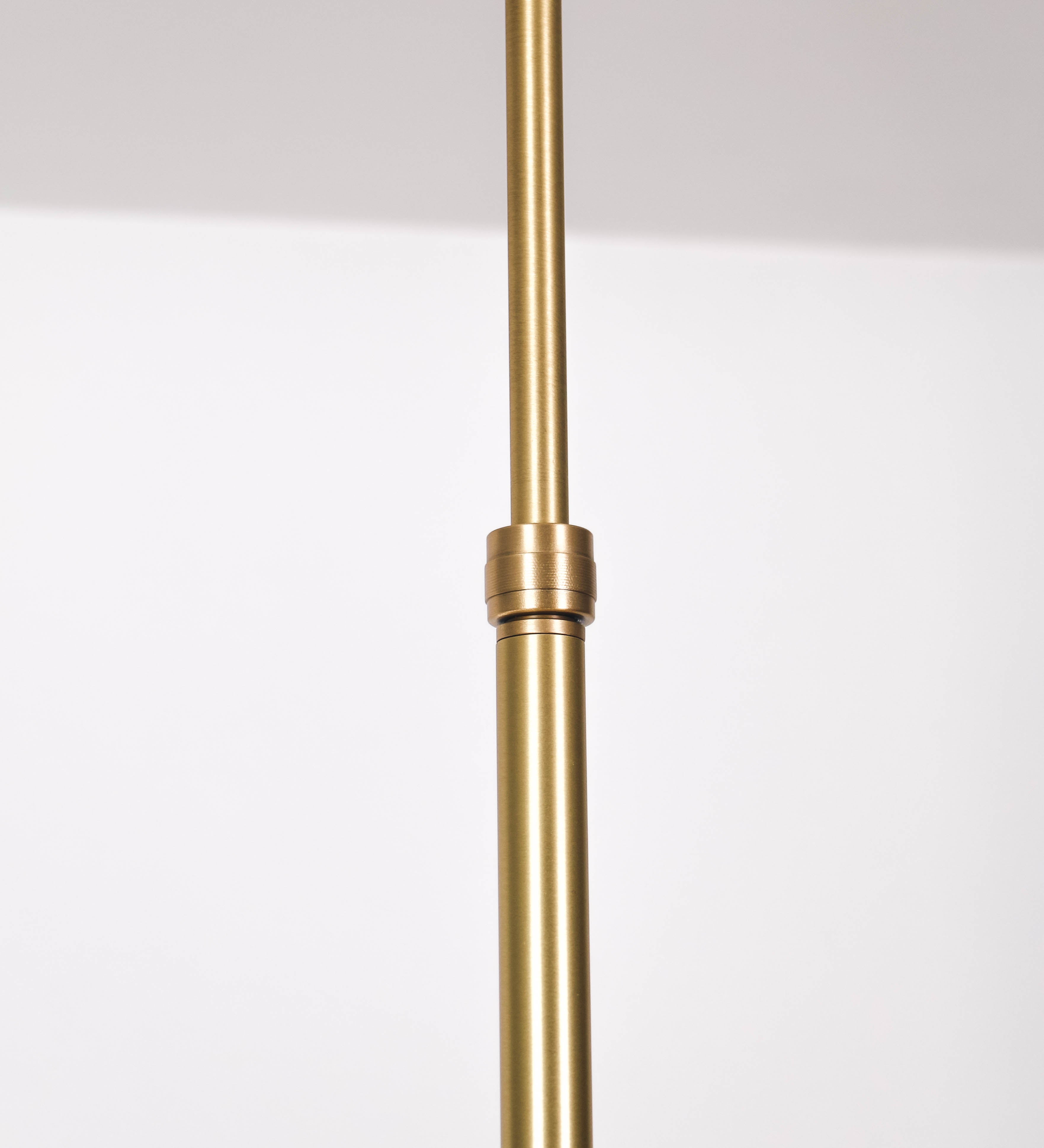 Suspensão de teto moderna e sofisticada. A suspensão é composta por uma base retangular em latão escovado, de onde desce um tubo cilíndrico até a estrutura principal e permite ajustar a altura da suspensão. A estrutura principal é composta por uma barra horizontal bege clara, que sustenta nas extremidades dois chapéus cónicos invertidos no mesmo tom, com interior em latão escovado. No centro da barra horizontal está uma pequena placa oval, em latão escovado, com o ano 1930 inscrito em relevo.