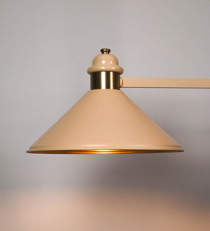 Suspensão de teto moderna e sofisticada. A suspensão é composta por uma base retangular em latão escovado, de onde desce um tubo cilíndrico até a estrutura principal e permite ajustar a altura da suspensão. A estrutura principal é composta por uma barra horizontal bege clara, que sustenta nas extremidades dois chapéus cónicos invertidos no mesmo tom, com interior em latão escovado. No centro da barra horizontal está uma pequena placa oval, em latão escovado, com o ano 1930 inscrito em relevo.