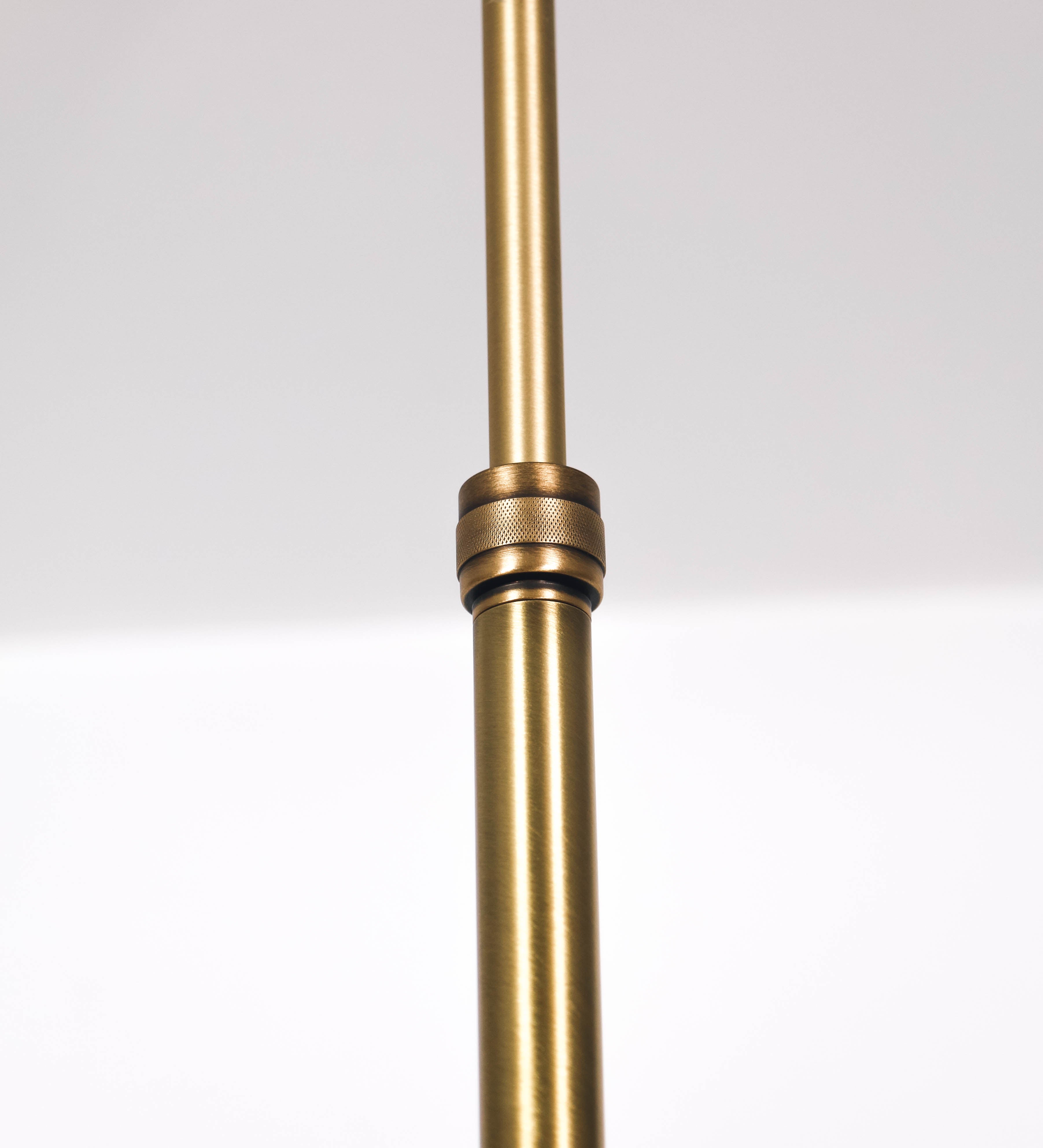 Suspensão de teto moderna e sofisticada. A suspensão é composta por uma base retangular em ouro velho, de onde desce um tubo cilíndrico até a estrutura principal e permite ajustar a altura da suspensão. A estrutura principal é composta por uma barra horizontal verde-azeitona, que sustenta nas extremidades dois chapéus cónicos invertidos no mesmo tom, com interior em ouro velho. No centro da barra horizontal está uma pequena placa oval, em ouro velho, com o ano 1930 inscrito em relevo.