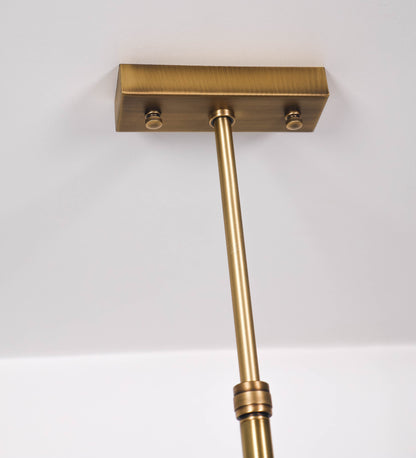 Suspensão de teto moderna e sofisticada. A suspensão é composta por uma base retangular em ouro velho, de onde desce um tubo cilíndrico até a estrutura principal e permite ajustar a altura da suspensão. A estrutura principal é composta por uma barra horizontal verde-azeitona, que sustenta nas extremidades dois chapéus cónicos invertidos no mesmo tom, com interior em ouro velho. No centro da barra horizontal está uma pequena placa oval, em ouro velho, com o ano 1930 inscrito em relevo.