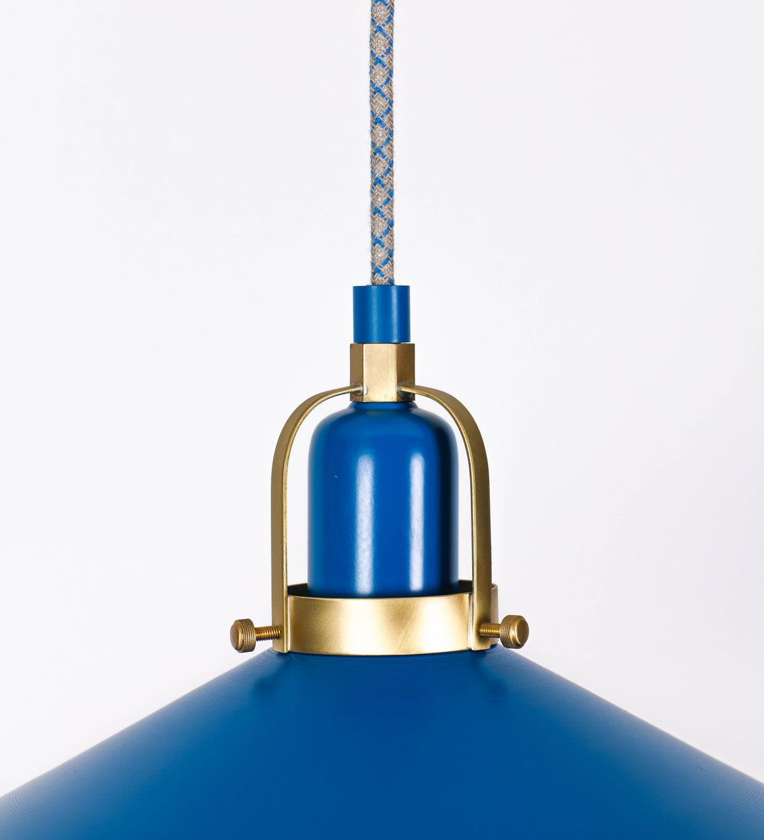 Suspensão de teto que combina um design clássico com cores modernas. A suspensão é fixa ao teto através de uma base circular azul vintage, de onde desce um cabo revestido têxtil com um padrão de linhas azuis e beges entrelaçadas, que sustenta o chapéu principal. O chapéu, azul vintage, tem um formato cónico invertido, com uma borda ligeiramente levantada. O interior do chapéu é branco. No topo do chapéu, há um suporte circular em latão escovado, com três pequenos braços que conecta o chapéu ao cabo.
