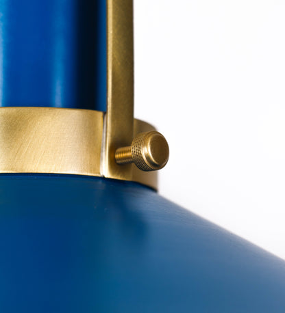 Suspensão de teto que combina um design clássico com cores modernas. A suspensão é fixa ao teto através de uma base circular azul vintage, de onde desce um cabo revestido têxtil com um padrão de linhas azuis e beges entrelaçadas, que sustenta o chapéu principal. O chapéu, azul vintage, tem um formato cónico invertido, com uma borda ligeiramente levantada. O interior do chapéu é branco. No topo do chapéu, há um suporte circular em latão escovado, com três pequenos braços que conecta o chapéu ao cabo.