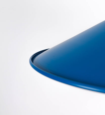 Suspensão de teto que combina um design clássico com cores modernas. A suspensão é fixa ao teto através de uma base circular azul vintage, de onde desce um cabo revestido têxtil com um padrão de linhas azuis e beges entrelaçadas, que sustenta o chapéu principal. O chapéu, azul vintage, tem um formato cónico invertido, com uma borda ligeiramente levantada. O interior do chapéu é branco. No topo do chapéu, há um suporte circular em latão escovado, com três pequenos braços que conecta o chapéu ao cabo.