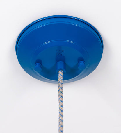 Suspensão de teto que combina um design clássico com cores modernas. A suspensão é fixa ao teto através de uma base circular azul vintage, de onde desce um cabo revestido têxtil com um padrão de linhas azuis e beges entrelaçadas, que sustenta o chapéu principal. O chapéu, azul vintage, tem um formato cónico invertido, com uma borda ligeiramente levantada. O interior do chapéu é branco. No topo do chapéu, há um suporte circular em latão escovado, com três pequenos braços que conecta o chapéu ao cabo.