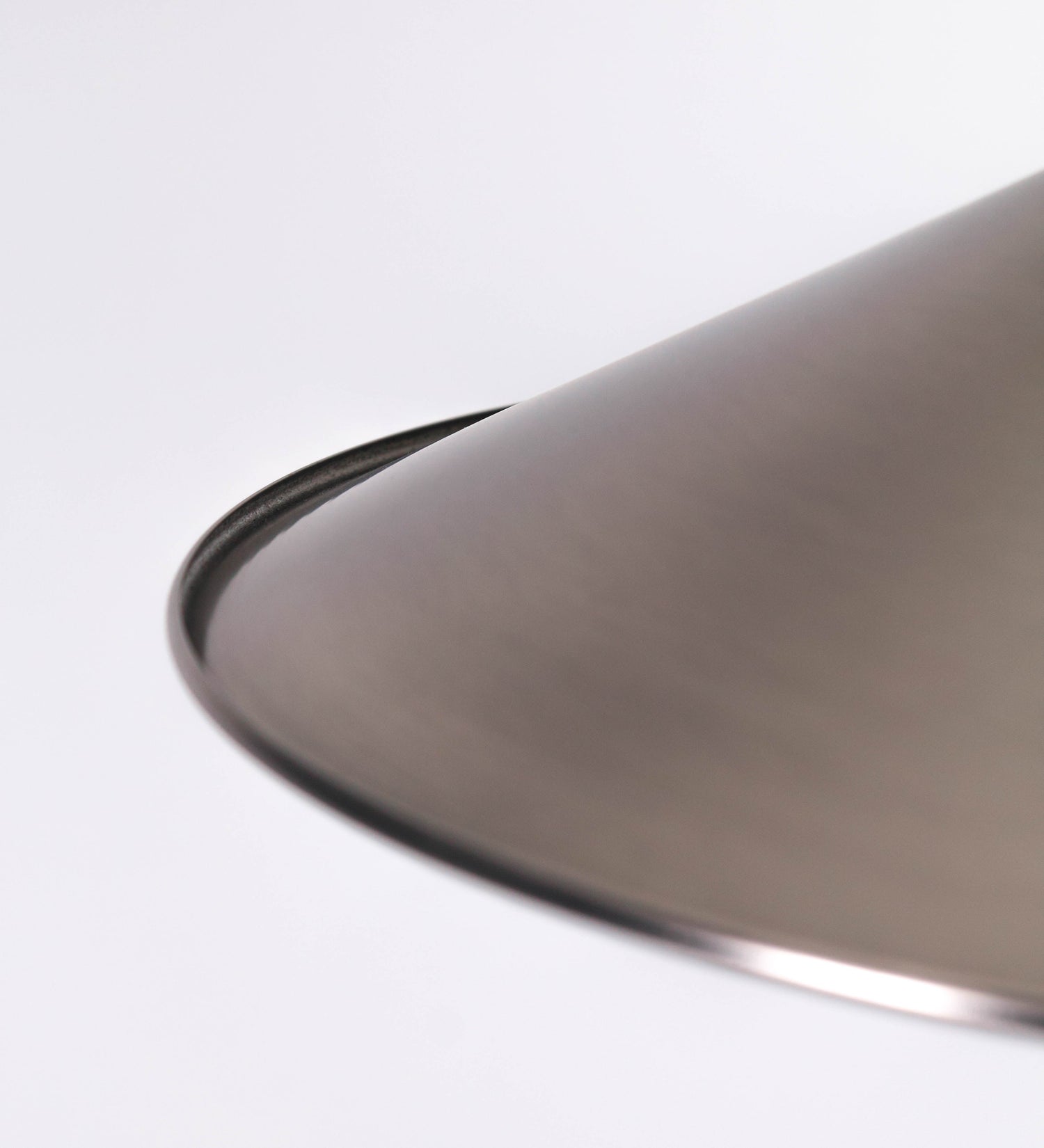 Suspensão de teto que combina um design clássico com um acabamento moderno e de estilo industrial. A suspensão, toda em níquel escovado, é fixa ao teto através de uma base circular de onde desce um cabo revestido têxtil preto, que sustenta o chapéu principal. O chapéu tem um formato cónico invertido, com uma borda ligeiramente levantada. No topo do chapéu, há um suporte circular com três pequenos braços que conecta o chapéu ao cabo.