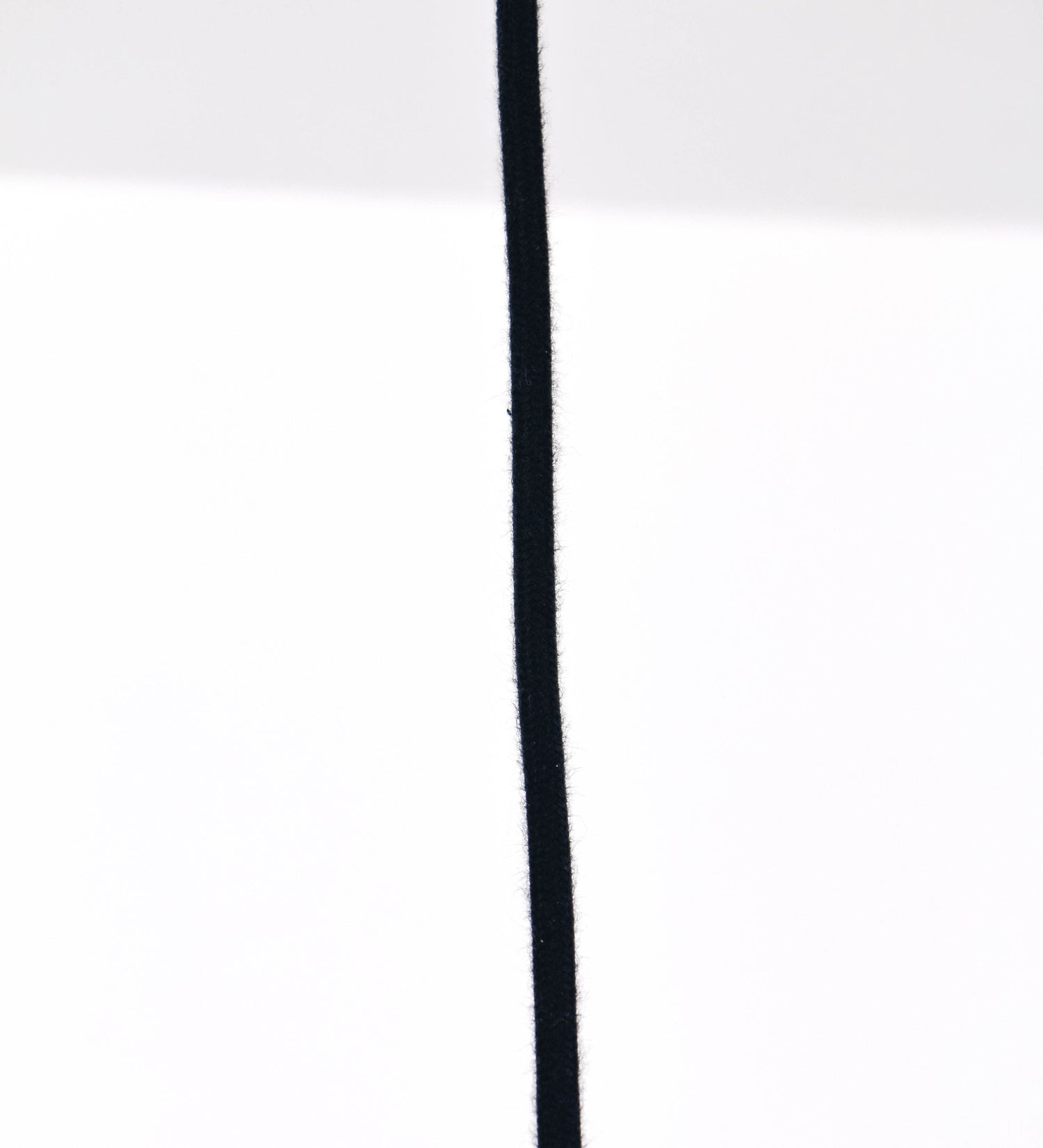 Suspensão de teto que combina um design clássico com um acabamento moderno e de estilo industrial. A suspensão, toda em níquel escovado, é fixa ao teto através de uma base circular de onde desce um cabo revestido têxtil preto, que sustenta o chapéu principal. O chapéu tem um formato cónico invertido, com uma borda ligeiramente levantada. No topo do chapéu, há um suporte circular com três pequenos braços que conecta o chapéu ao cabo.