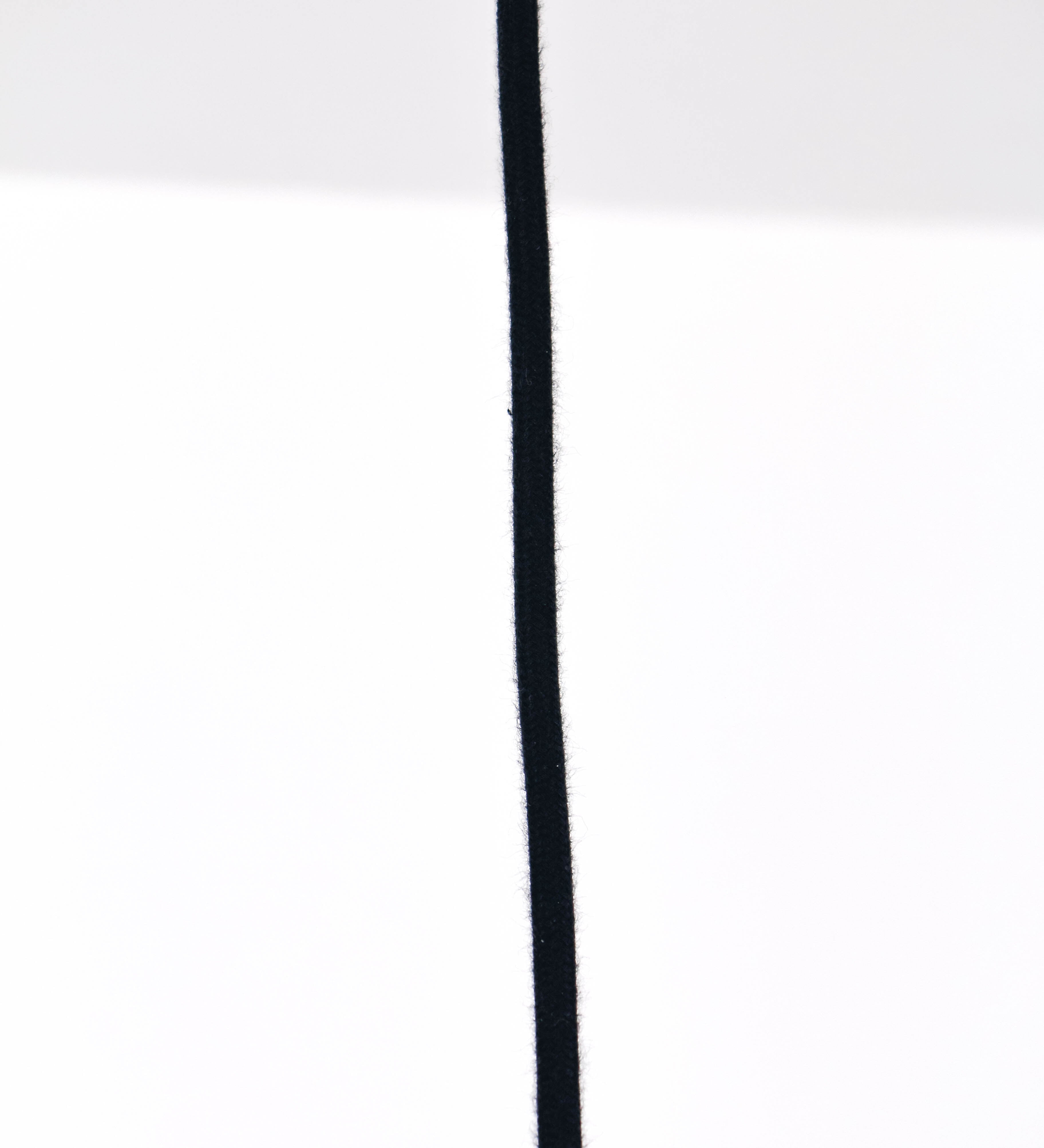 Suspensão de teto que combina um design clássico com um acabamento moderno e de estilo industrial. A suspensão, toda em níquel escovado, é fixa ao teto através de uma base circular de onde desce um cabo revestido têxtil preto, que sustenta o chapéu principal. O chapéu tem um formato cónico invertido, com uma borda ligeiramente levantada. No topo do chapéu, há um suporte circular com três pequenos braços que conecta o chapéu ao cabo.
