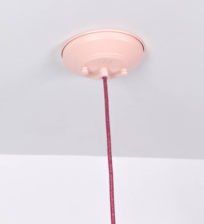 Suspensão de teto que combina um design clássico com cores modernas. A suspensão é fixa ao teto através de uma base circular rosa clara, de onde desce um cabo revestido têxtil rosa velho, que sustenta o chapéu principal. O chapéu, rosa claro, tem um formato cónico invertido, com uma borda ligeiramente levantada. O interior do chapéu é branco. No topo do chapéu, há um suporte circular em níquel polido, com três pequenos braços que conecta o chapéu ao cabo.