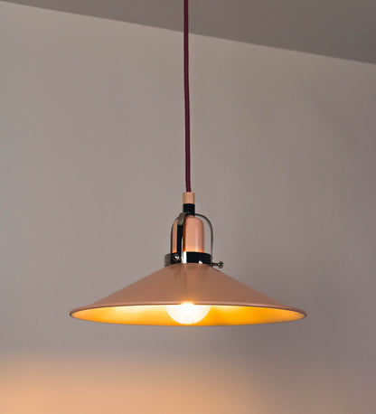 Suspensão de teto que combina um design clássico com cores modernas. A suspensão é fixa ao teto através de uma base circular rosa clara, de onde desce um cabo revestido têxtil rosa velho, que sustenta o chapéu principal. O chapéu, rosa claro, tem um formato cónico invertido, com uma borda ligeiramente levantada. O interior do chapéu é branco. No topo do chapéu, há um suporte circular em níquel polido, com três pequenos braços que conecta o chapéu ao cabo.
