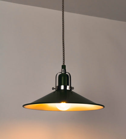 Suspensão de teto que combina um design clássico e cores modernas. A suspensão é fixa ao teto através de uma base circular verde couve-de-bruxelas, de onde desce um cabo revestido têxtil com um padrão de linhas castanhas e beges entrelaçadas, que sustenta o chapéu principal. O chapéu, verde, tem um formato cónico invertido, com uma borda ligeiramente levantada. O interior do chapéu é branco. No topo do chapéu, há um suporte circular em níquel escovado, com três pequenos braços que conecta o chapéu ao cabo.